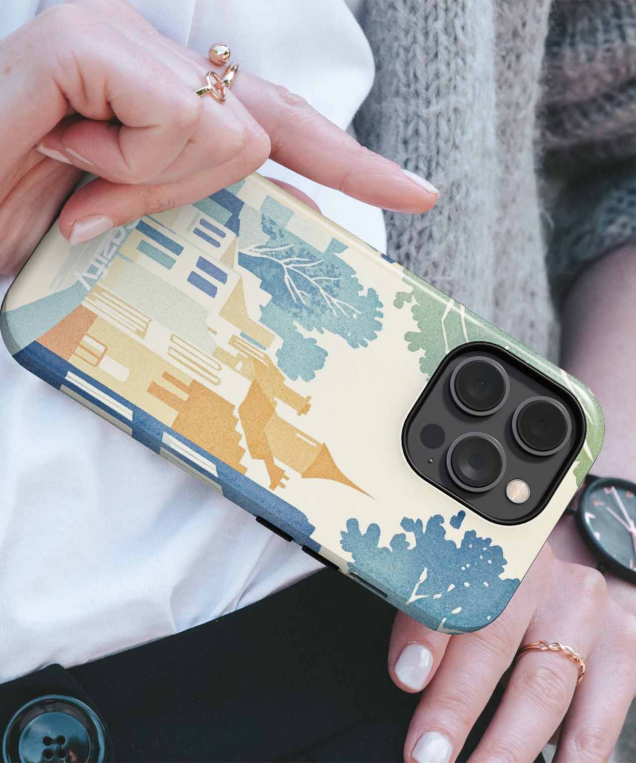 Glossy phone case with abstract blue, beige, and green tree and mountain design on black triple-camera iPhone. - Cazify Canada