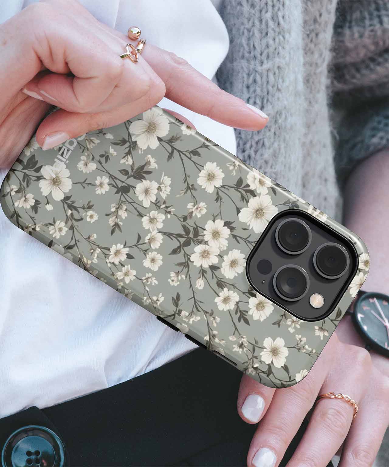 Green floral patterned phone case with white flowers on an iPhone with triple camera lenses. - Cazify Canada