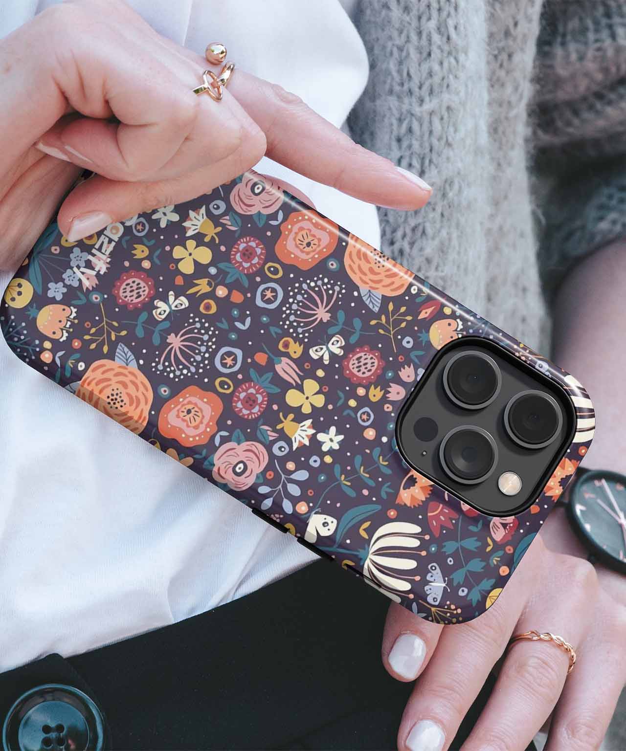 Floral patterned phone case with orange, yellow, and white flowers on dark background covering a black smartphone. - Cazify Canada