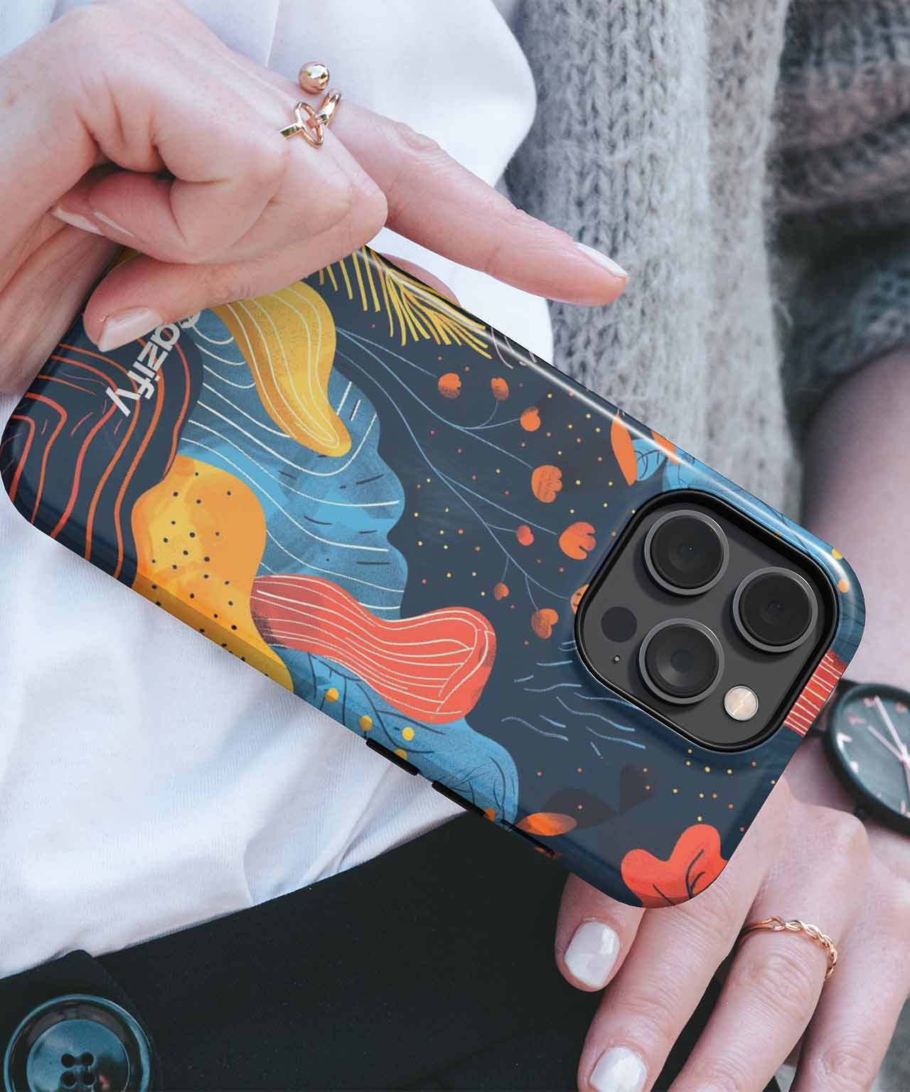 Colorful abstract floral design phone case on dark background, fitted on dark blue iPhone with triple camera lenses. - Cazify Canada