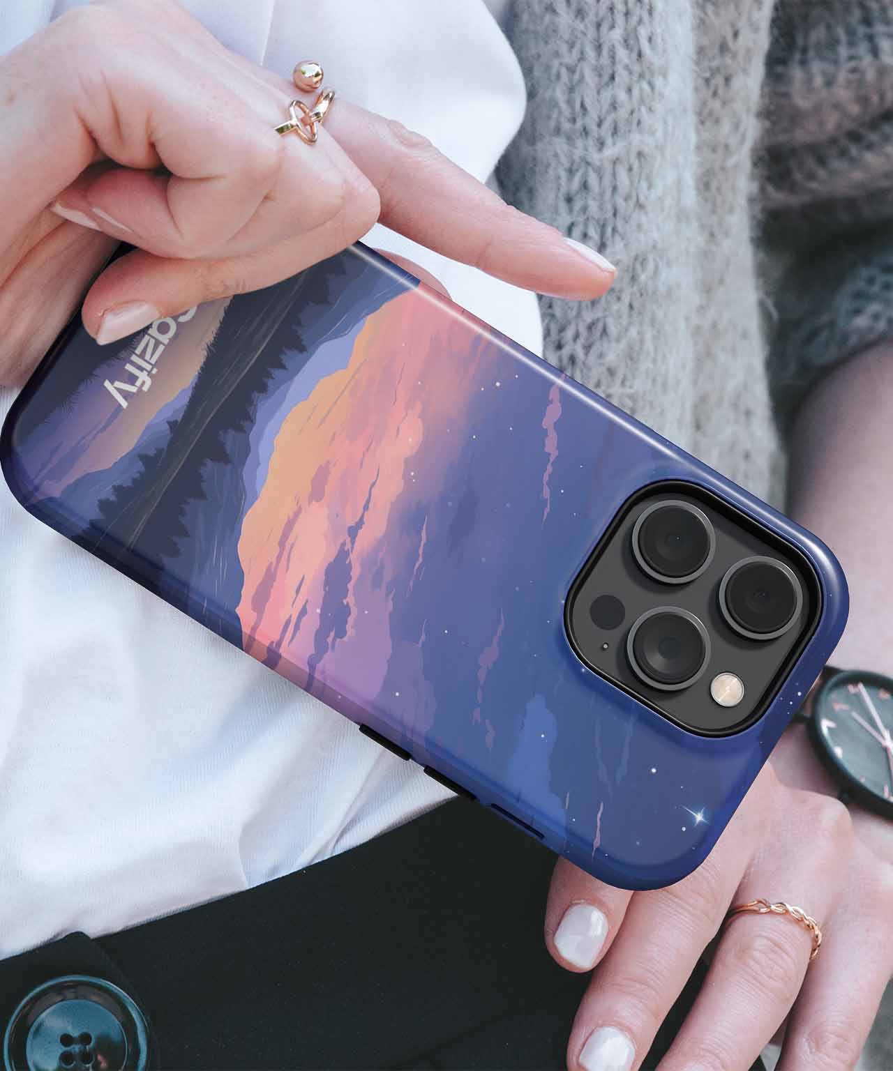 Cazify Canada - IPhone with a navy blue case featuring a mountain sunset design and triple camera lenses.