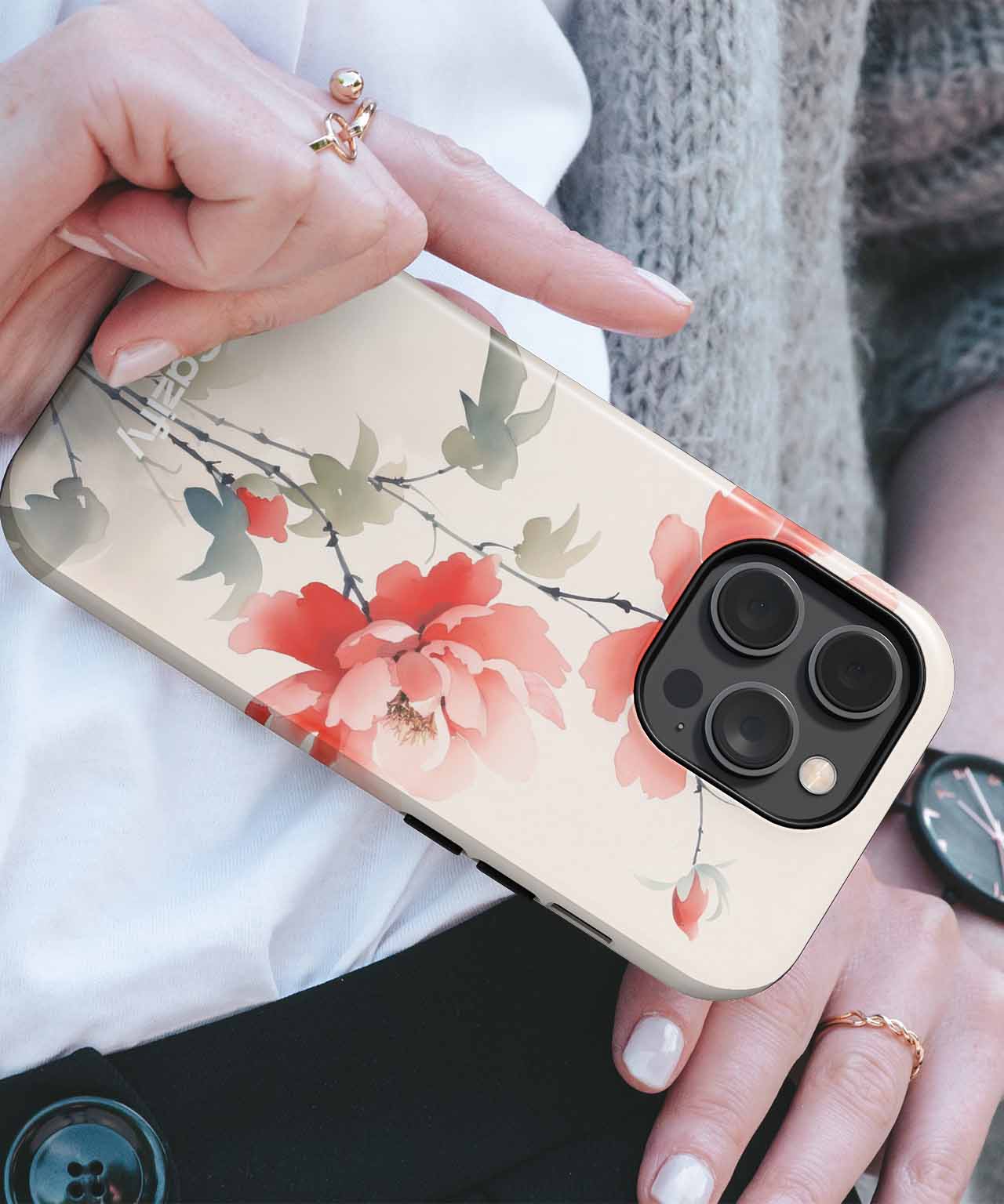 Cream-colored phone case with large red and pink floral design and green leaves on an iPhone model. - Cazify Canada