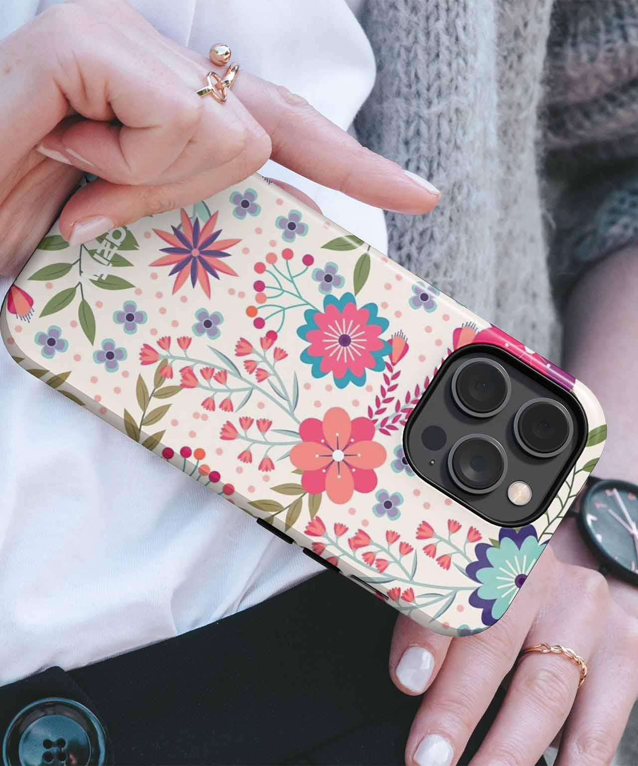 Cream-colored floral iPhone case with red, blue, and pink flowers, held in hand. - Cazify Canada