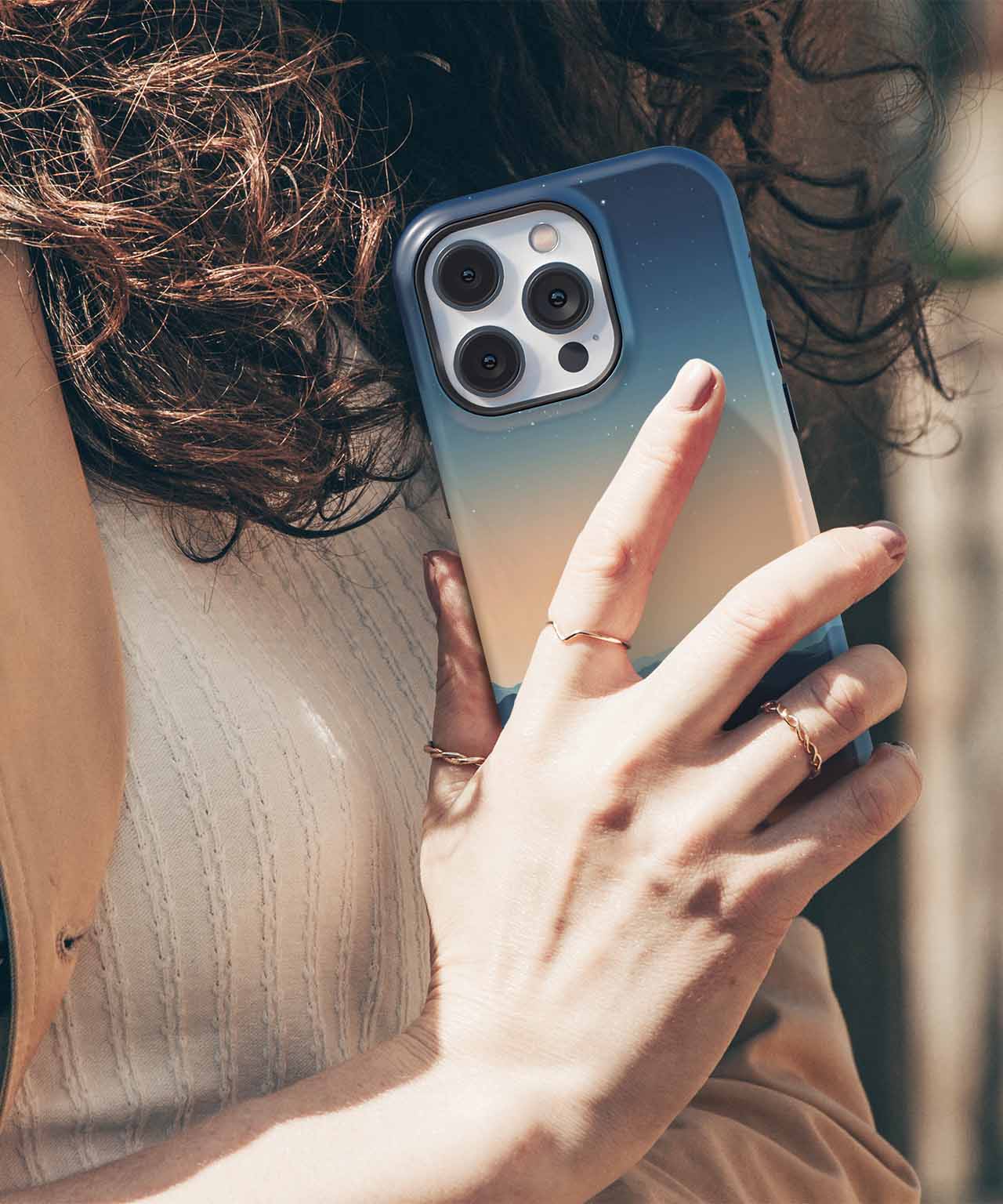 Cazify Canada - Blue to gray gradient iPhone case with large camera cutout, held by a hand with rings.