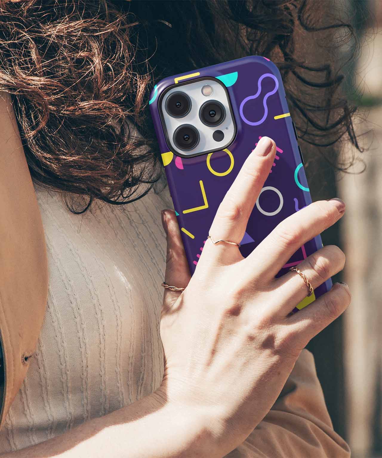Navy blue iPhone case with colorful geometric shapes and gold ring detail on hand. - Cazify Canada
