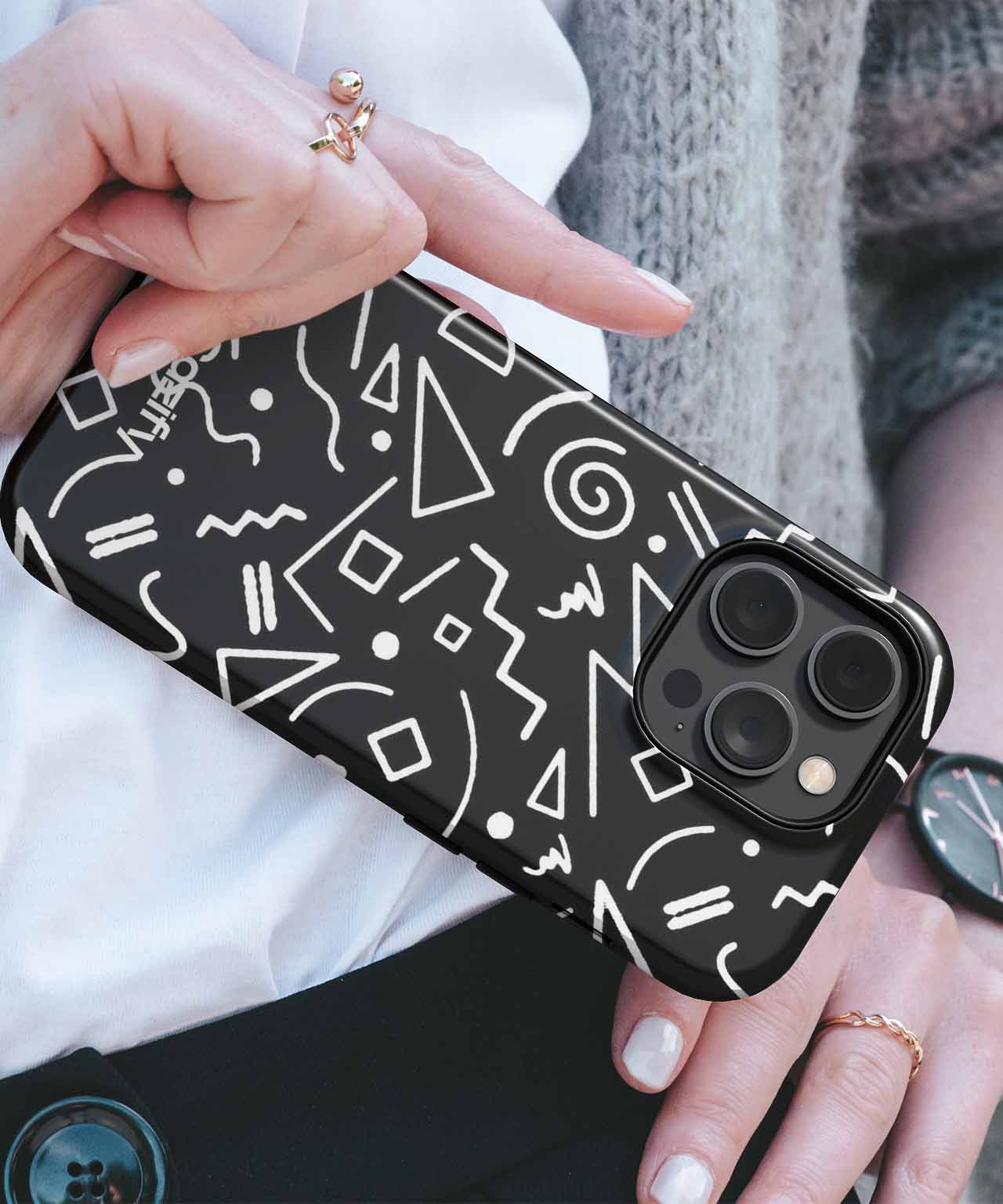 Black phone case with white abstract geometric shapes and patterns on an iPhone with triple camera lenses. - Cazify Canada