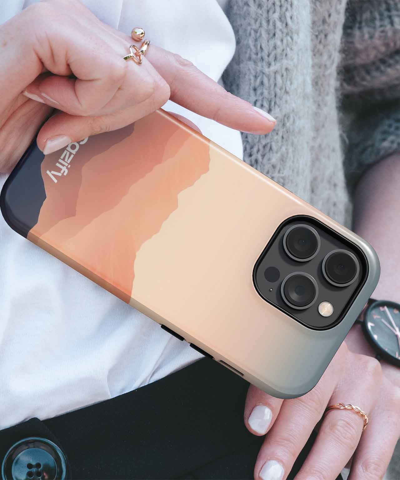 Cazify Canada - IPhone with sunset gradient case and triple camera lenses held in hand.