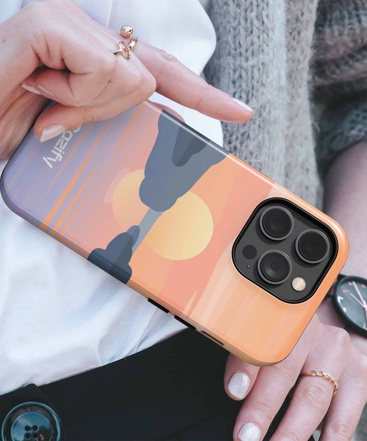Cazify Canada - IPhone with sunset-themed case showing sun and silhouette on beach scene.