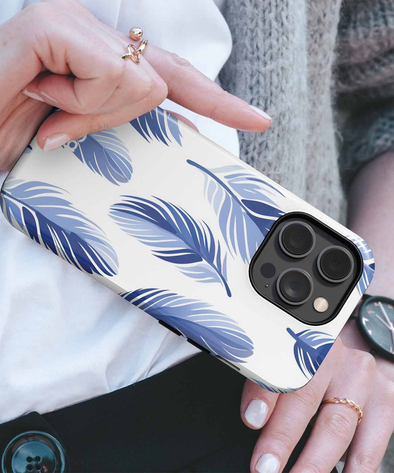 White phone case with blue feather pattern and black camera cutout on hand. - Cazify Canada