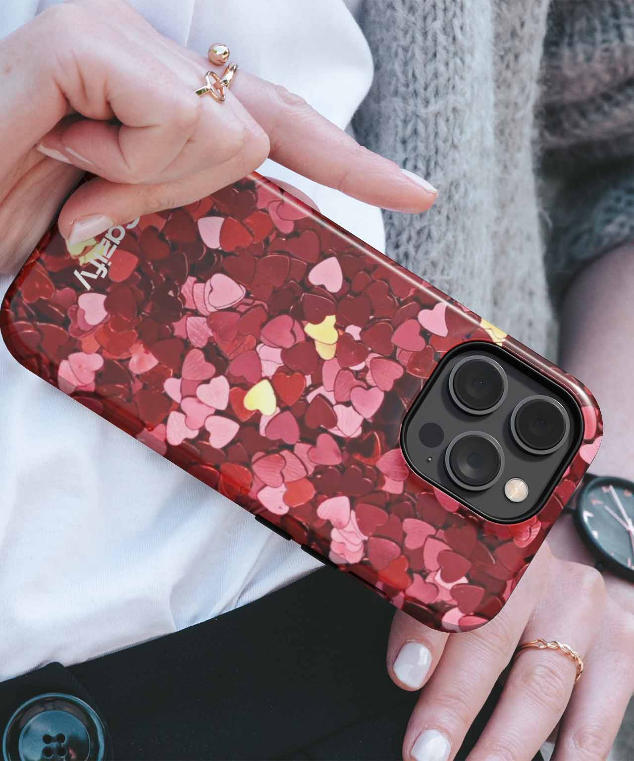 Red and pink heart-patterned iPhone case with gold accents on a phone with triple cameras. - Cazify Canada