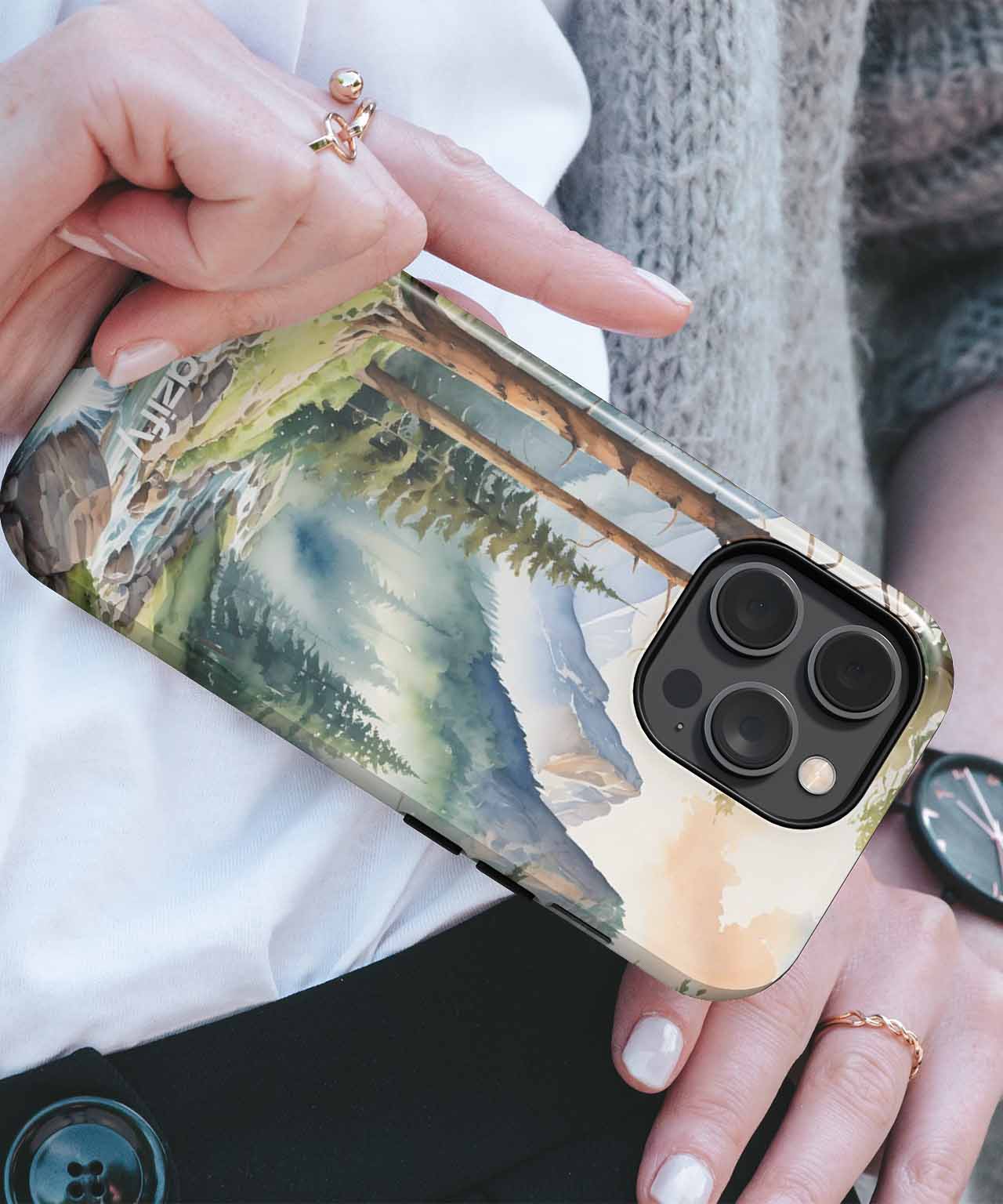 Cazify Canada - IPhone with protective case featuring mountain and forest landscape design.