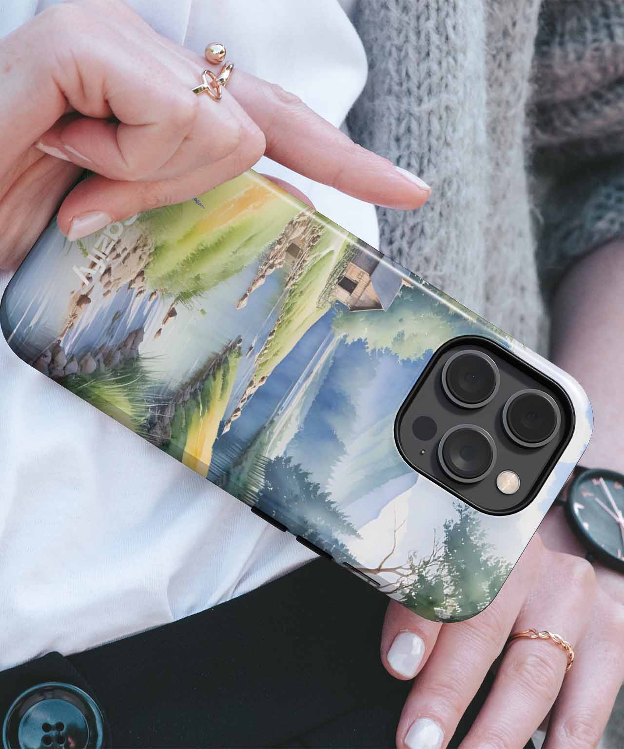 Cazify Canada - IPhone with landscape painting case featuring mountains, trees, and a river under a cloudy sky.