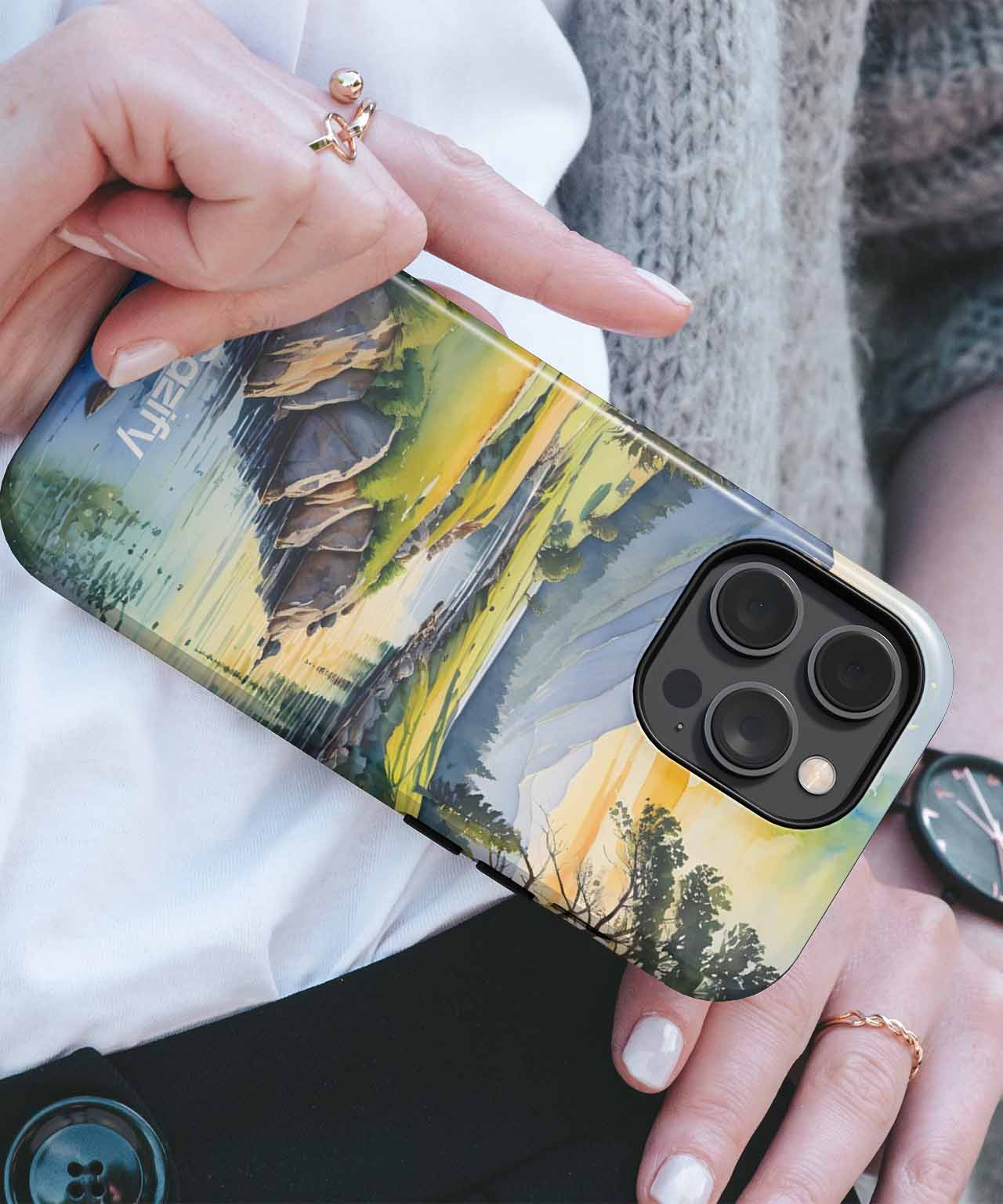 Cazify Canada - IPhone with artistic landscape phone case showing mountains, trees, and a river in green and yellow tones.
