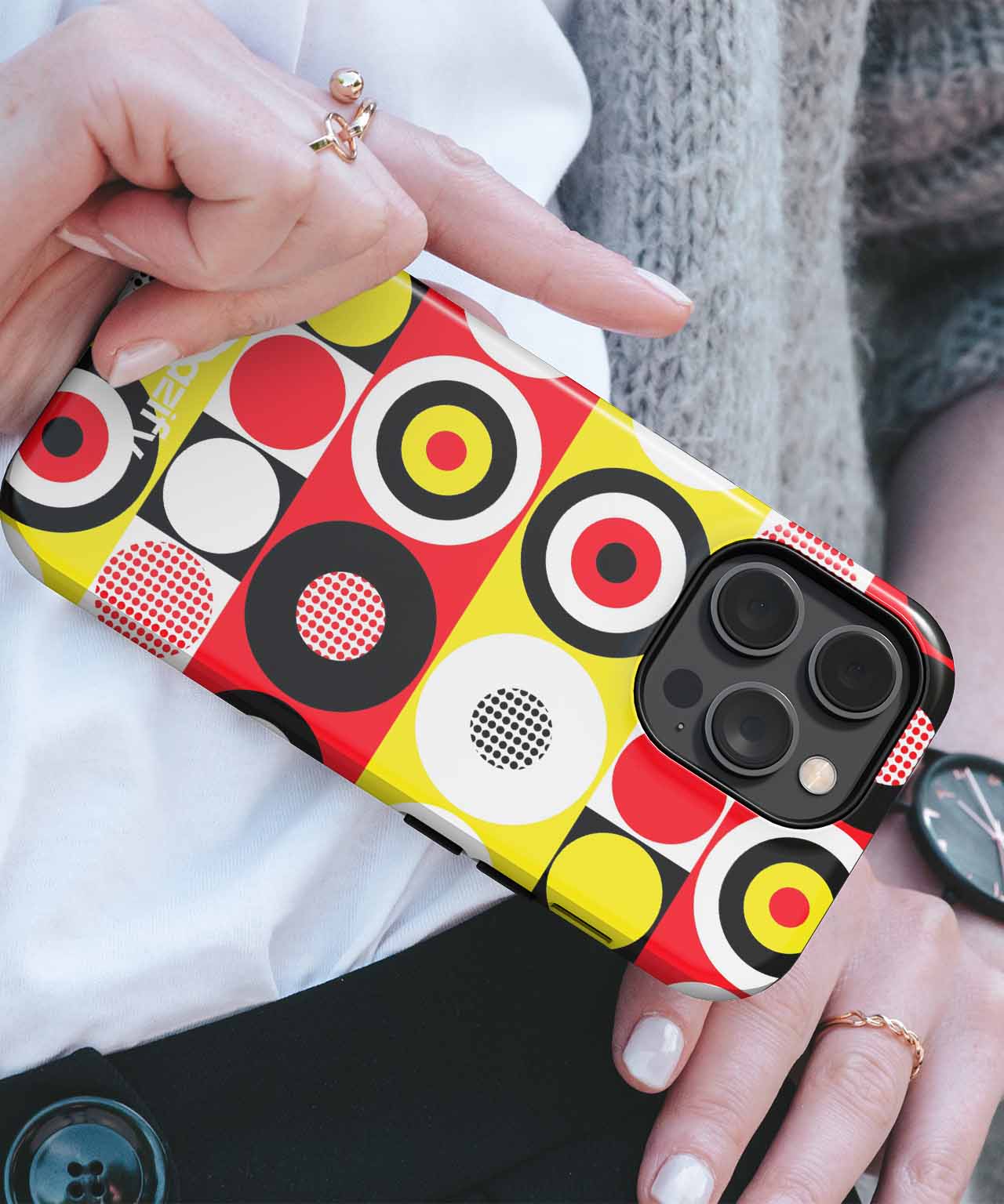 Colorful geometric patterned iPhone case with red, yellow, black, and white circles and squares on a black phone. - Cazify Canada