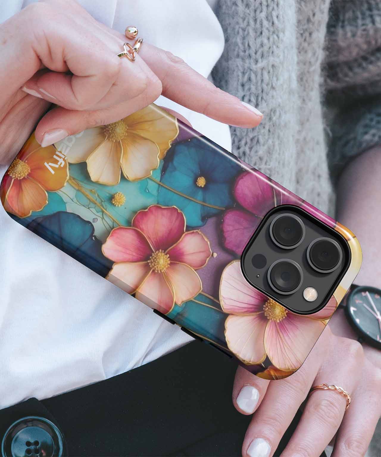 Colorful floral patterned phone case with pink, cream, and blue flowers on an iPhone with triple camera lenses. - Cazify Canada