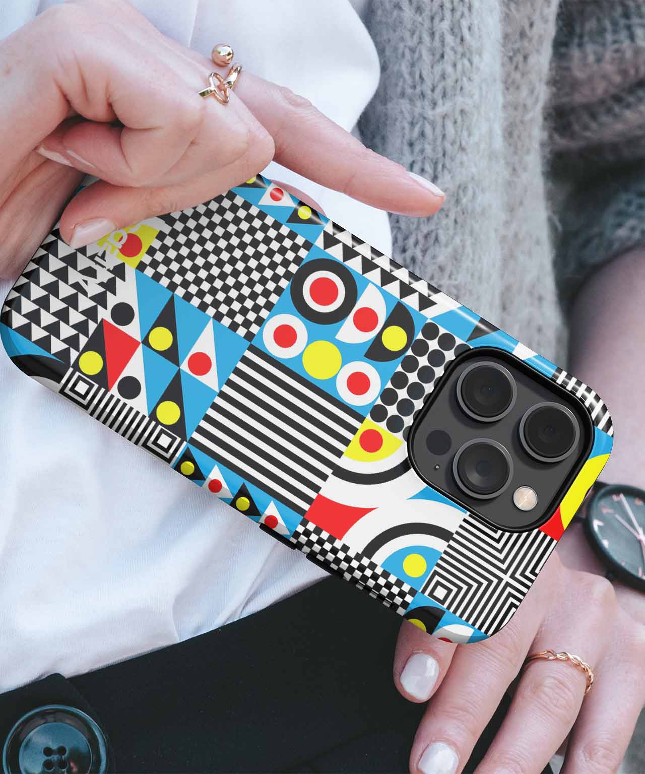 IPhone with colorful geometric patterned protective case featuring circles, stripes, and checkerboard designs. - Cazify Canada