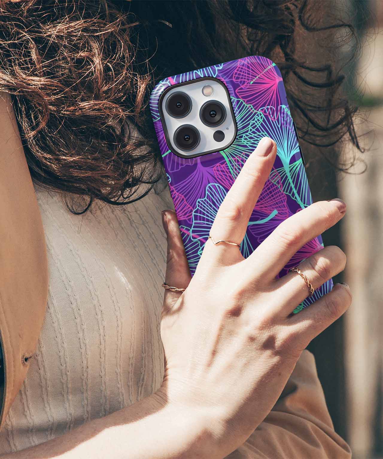 Purple and blue floral patterned iPhone case with triple camera cutout on a person’s hand. - Cazify Canada