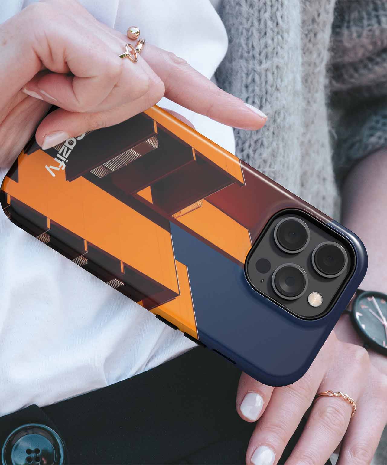 Black and orange geometric patterned iPhone case with camera cutout, held in hand with rings. - Cazify Canada
