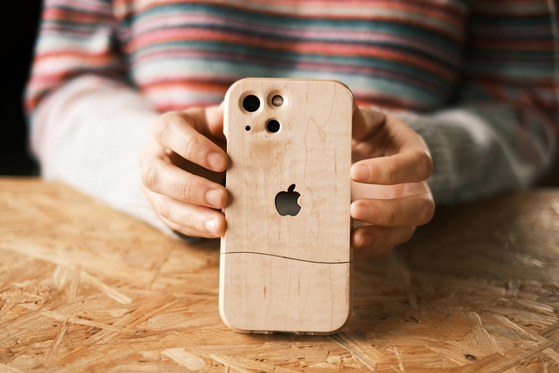 a person holding a wooden iphone case on a table