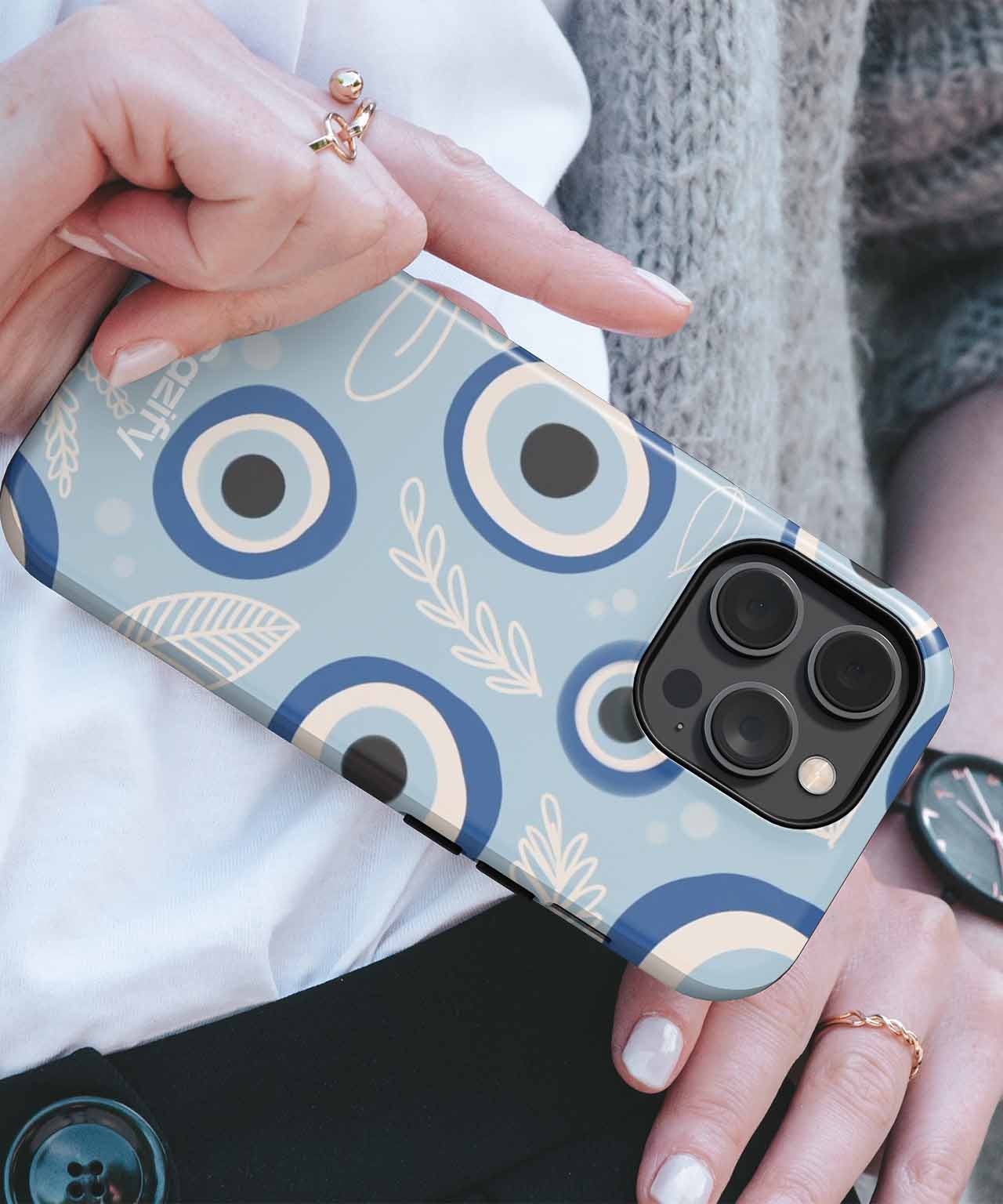 Blue iPhone case with eye pattern and leaf illustrations, held in a person's hand. - 0jhi4e-01 - Charming Blue Eye Pattern Vibes iPhone case