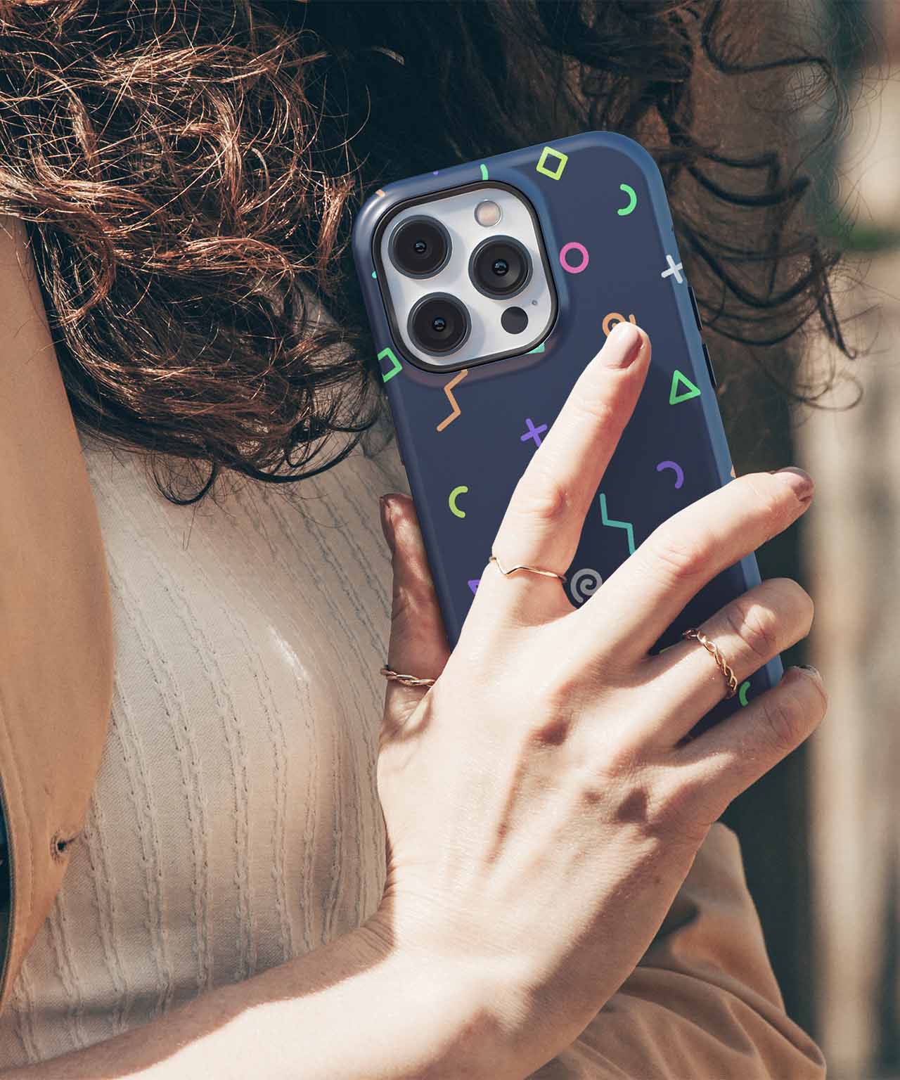Dark blue iPhone case with colorful geometric shapes on a smartphone held by a hand. - Cazify Canada