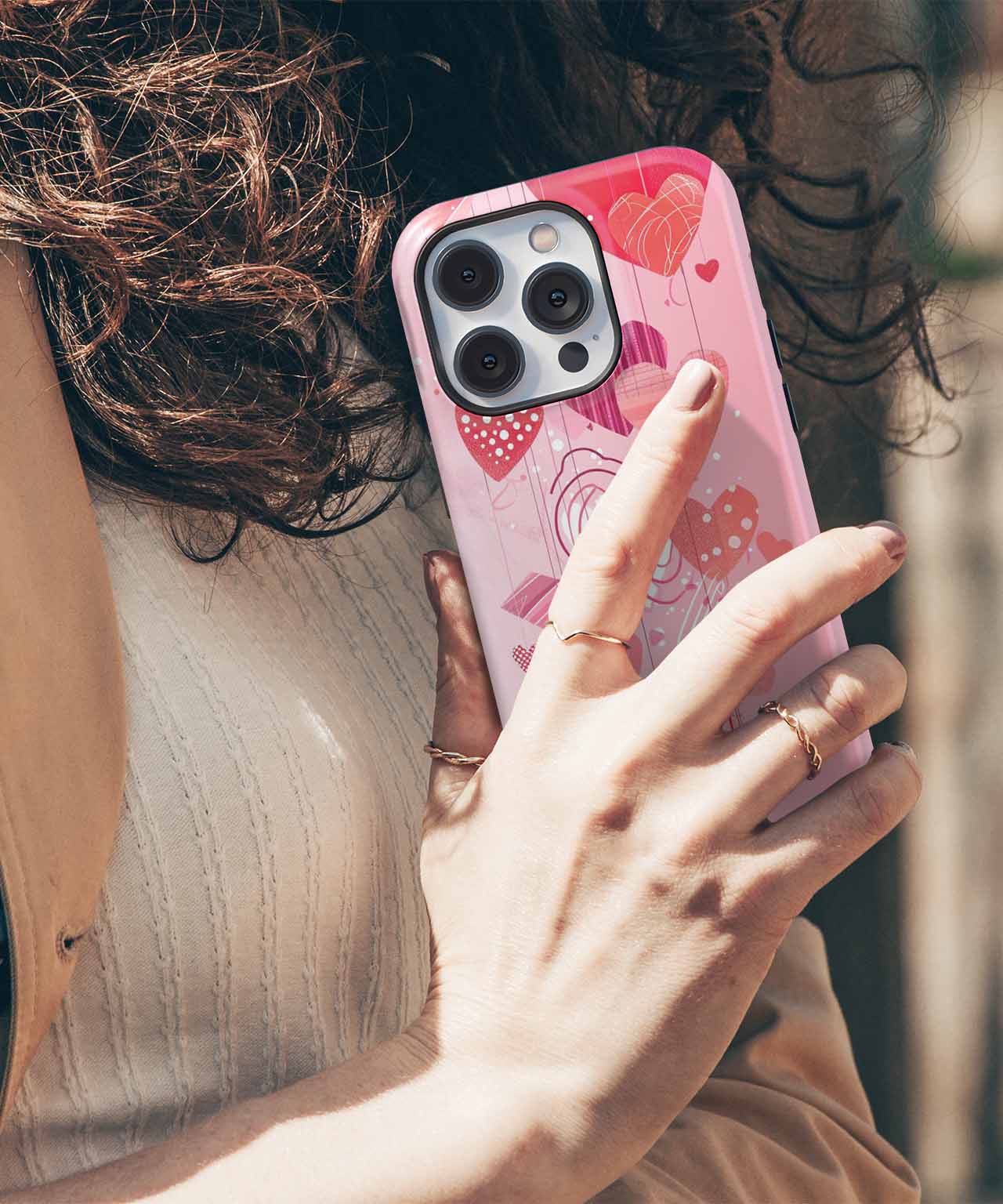 Pink iPhone case with red and pink heart patterns on a white sweater background. - Cazify Canada